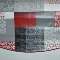 Toile cirée ronde pour 4 à 6 couverts avec un patchwork de motifs géométriques en gris-noir et rouge-bordeaux finie par un biais