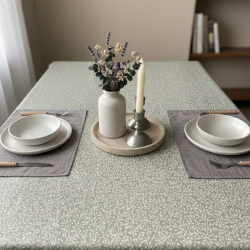 Toile cirée au mètre Rani, en 180 cm de largeur, un motif végétal délicat couleur crème sur fond taupe sur votre table...